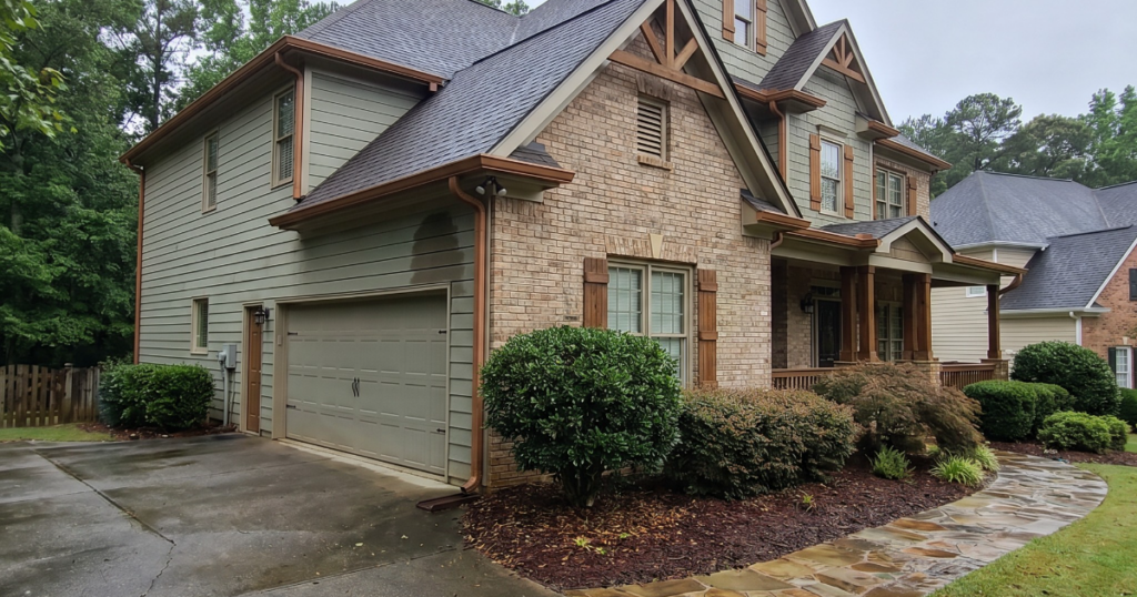 Well-kept Georgia home exterior after rain with roofline, gutters, and wet driveway for policy language and damage-cause review.