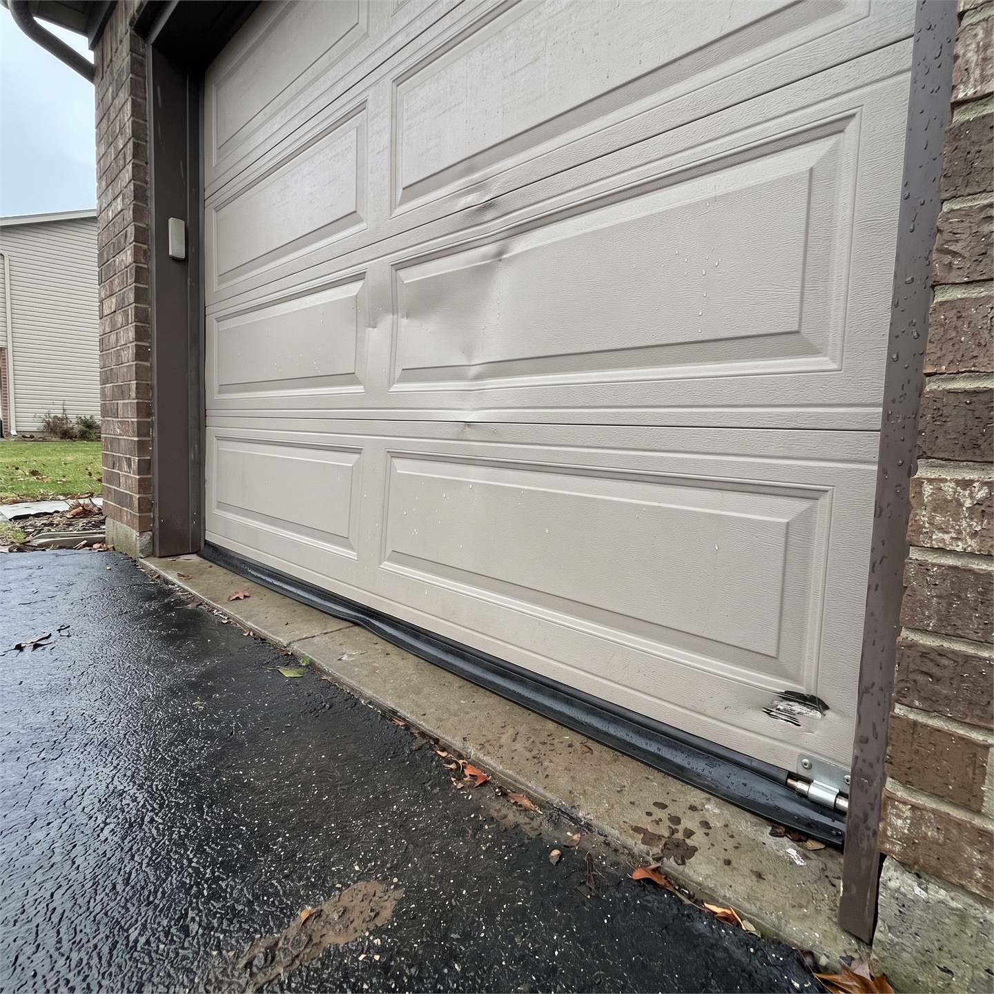 Wind-bent sectional garage door panels on a residential house after recent storms