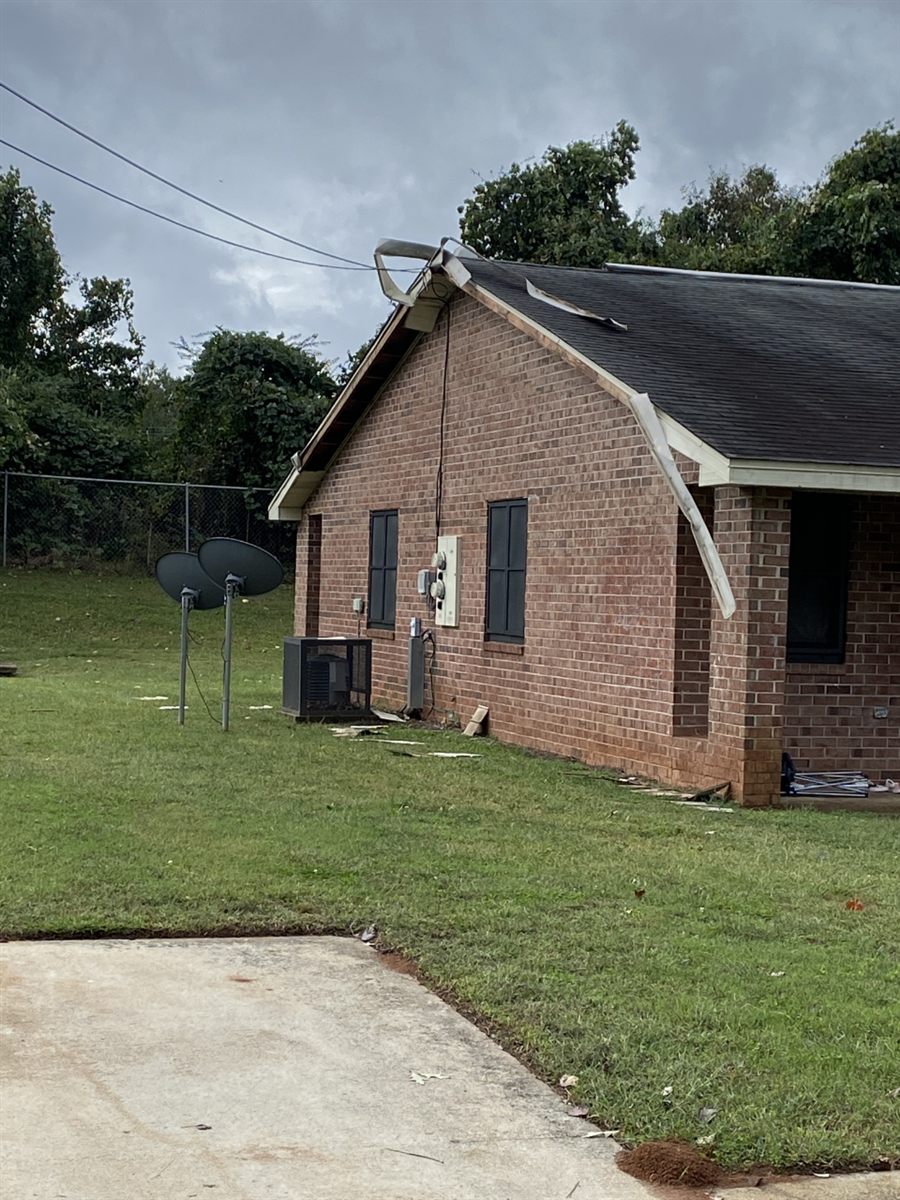Older Georgia brick residence with localized lifted roof-edge metal and detached exterior trim after wind damage