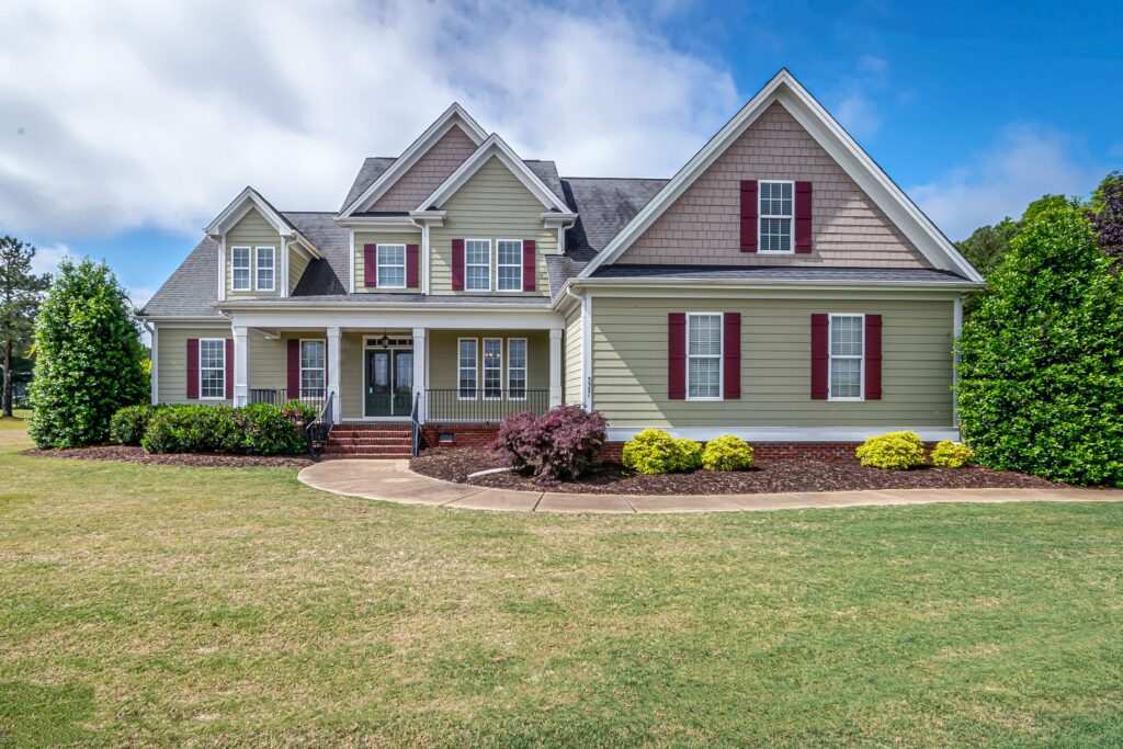 Two-story suburban home with several shingle-roof sections, front porch and lawn; illustrative stock property.