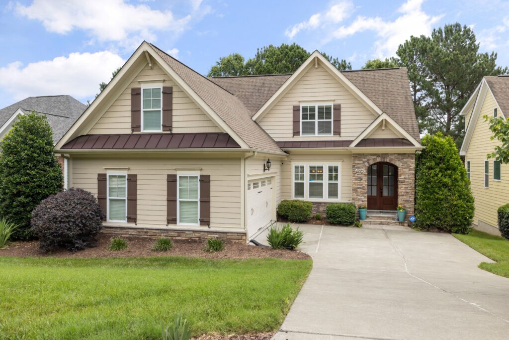 Whole suburban house with a shingle roof, front lawn, driveway and trees; illustrative stock property.