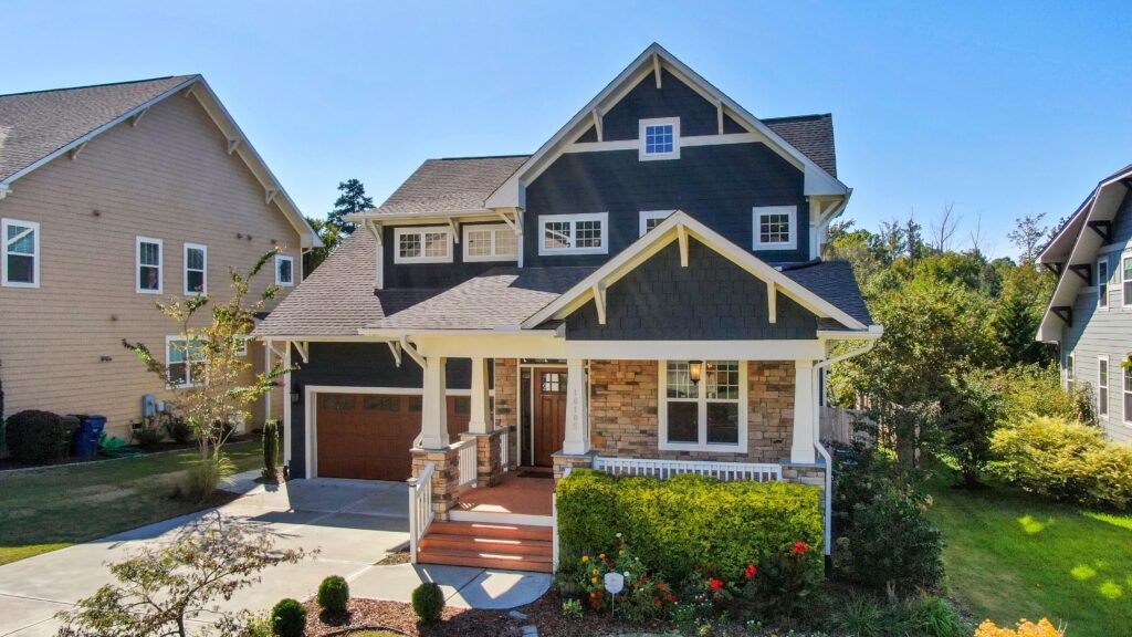 A blue and stone house with a porch, garage and shingle roof in Raleigh, North Carolina. Illustrative stock property.