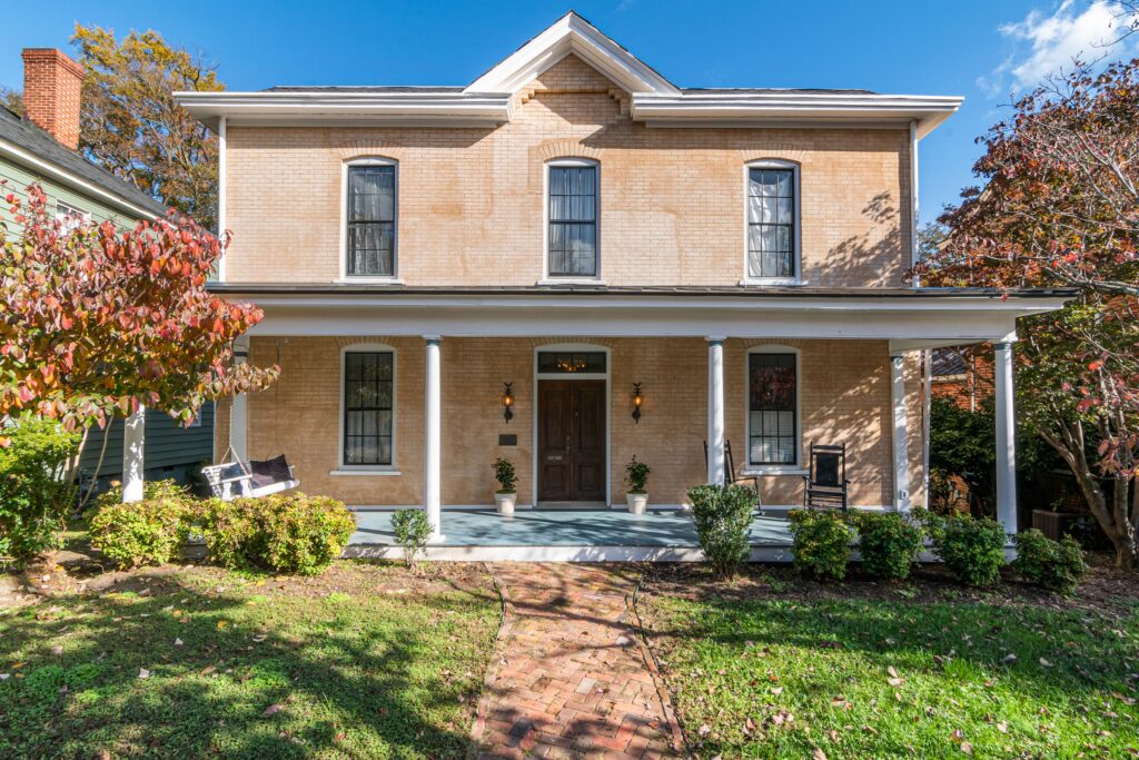 A two story brick home with a front porch and trees. Illustrative stock property, not the damaged home described in the example.