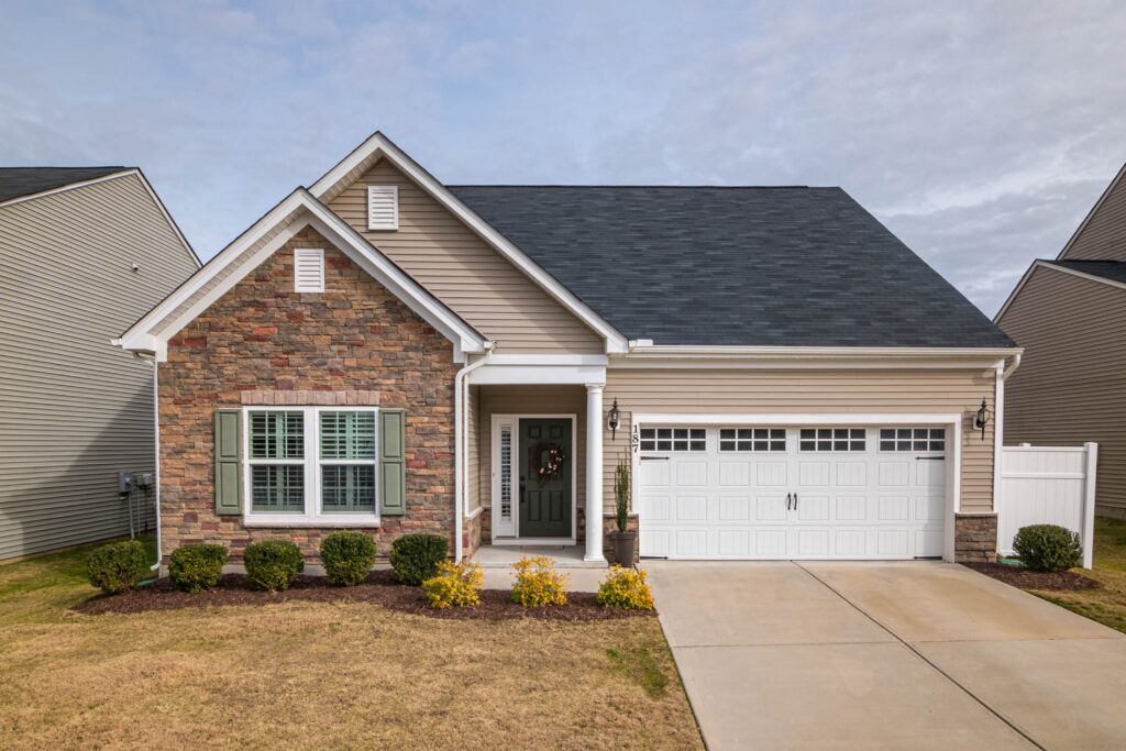 A complete suburban home with stone facing, siding, shingle roof and garage. Illustrative stock property, not a documented loss.