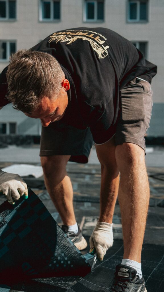 Stock photograph of a worker laying roof shingles. This is not Peggy Moore’s home or anyone involved in her State Farm case.